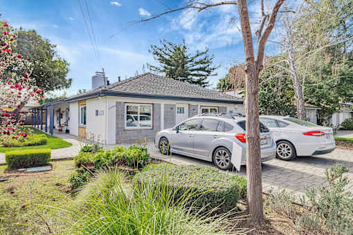 A grey house with a silver car parked in front.