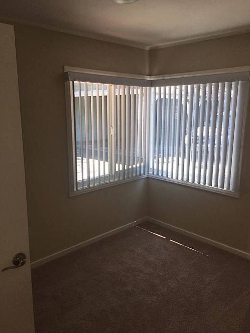 A room with a carpeted floor and a window with blinds.