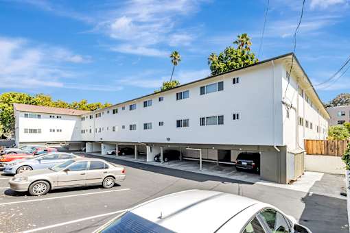 A white building with a parking lot in front of it.