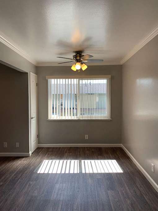 A room with a ceiling fan and a window with blinds.