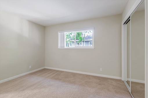 Empty room with a window and carpeted floor.