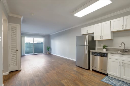 A kitchen with a refrigerator, sink, and cabinets.