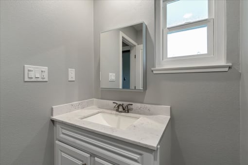a bathroom with a sink and a mirror and a window