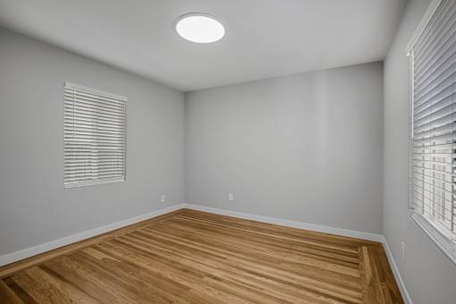 A room with wooden flooring and a window with blinds.