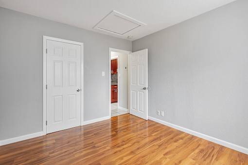 A room with two white doors and a wooden floor.