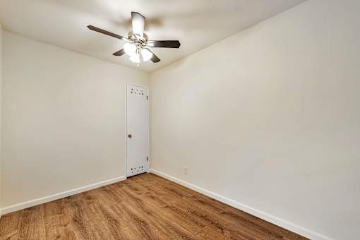 A room with a ceiling fan and a white door.