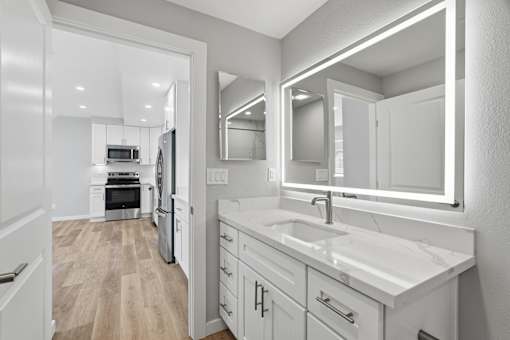 A modern kitchen with a white countertop and a large mirror above the sink.