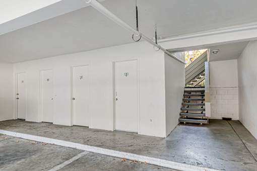 A room with white walls and a concrete floor with a staircase on the right side.
