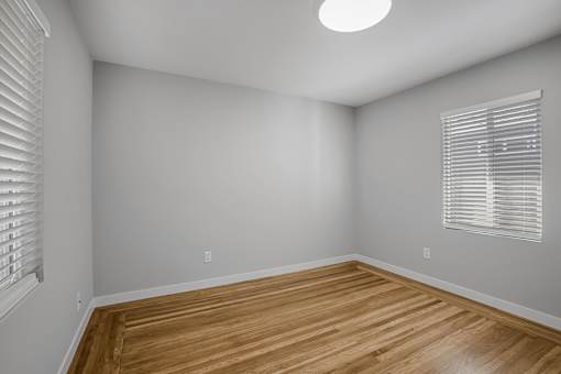 A room with wooden flooring and a window with blinds.