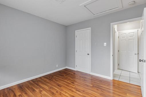 A room with wooden floors and two white doors.