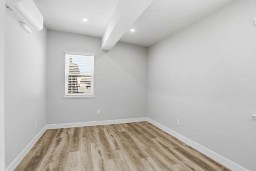 A room with wooden flooring and a window with blinds.