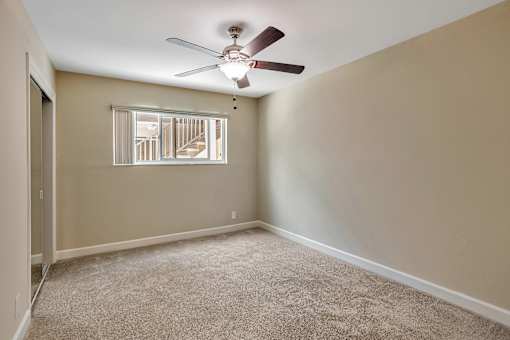 A room with a ceiling fan and carpeted floor.