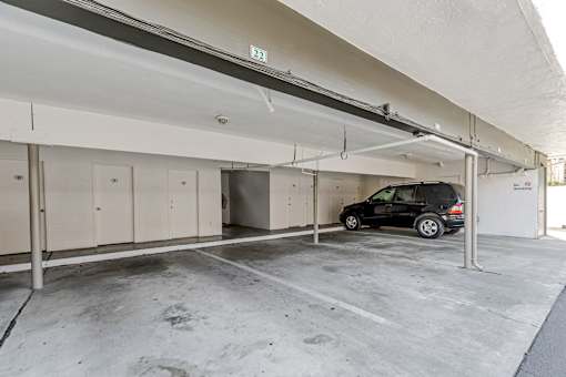 A black car is parked in a garage with a white ceiling.