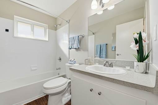 A white bathroom with a toilet, sink, and mirror.