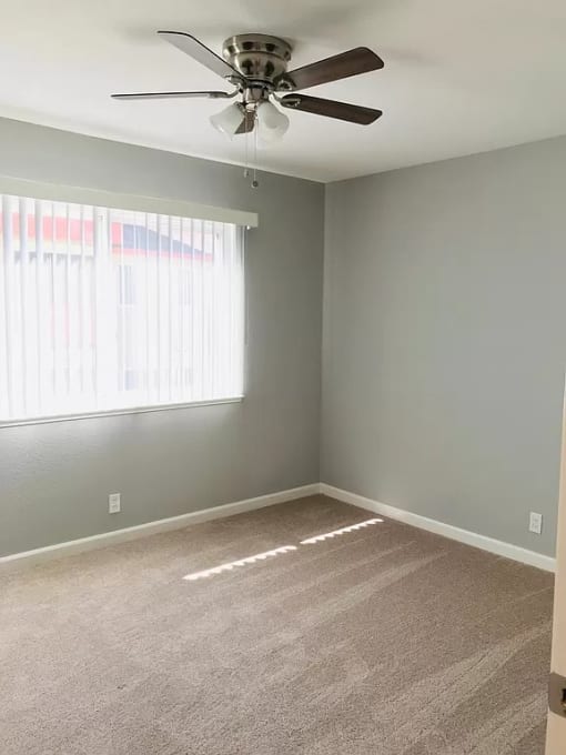 an empty room with a ceiling fan and a window