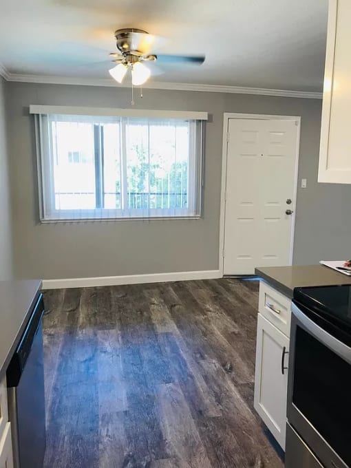 an empty kitchen with wood floors and a window