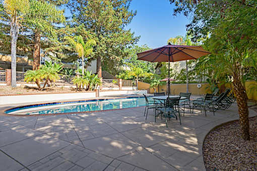 A patio with a table and chairs and a pool.
