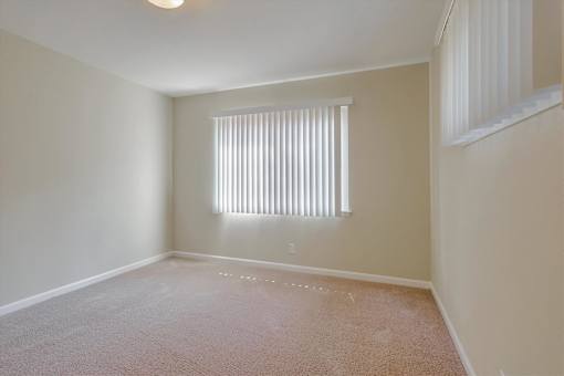 A room with a window covered by white blinds.