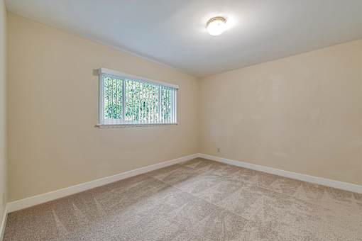 A room with a window and carpeted floor.