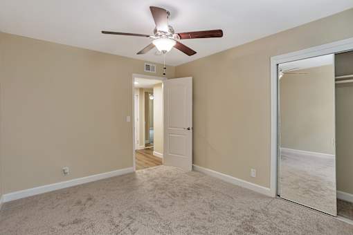 A room with a ceiling fan and a mirror on the wall.