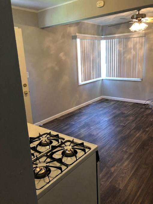 A room with a stove and a window with blinds.