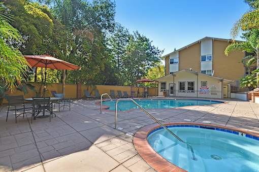 A pool with a hot tub and a building in the background.