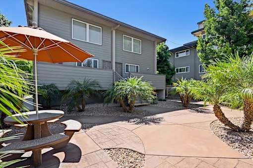 A patio with a table and chairs is surrounded by a garden.