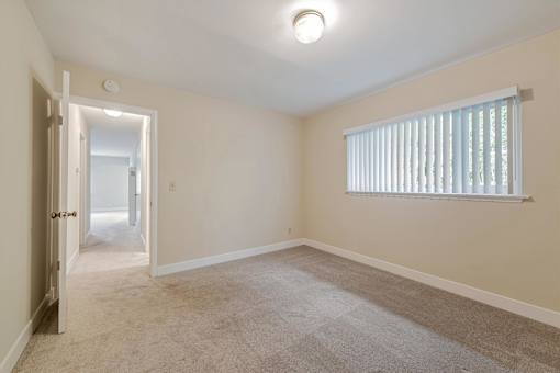A room with a carpeted floor and a window with blinds.