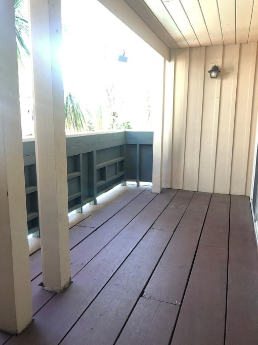 an empty porch with wood floors and a large window