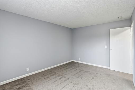 A room with a carpeted floor and a white door.