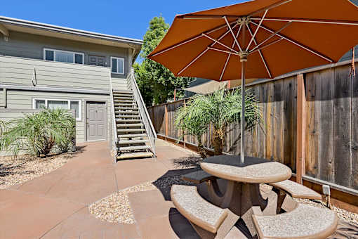 A patio with a table and chairs and an umbrella.