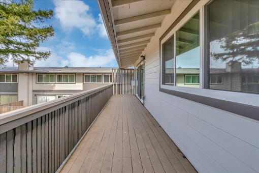 a long balcony with a wood floor and a large window