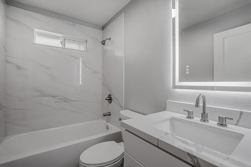 A white bathroom with a tub, toilet, and sink.