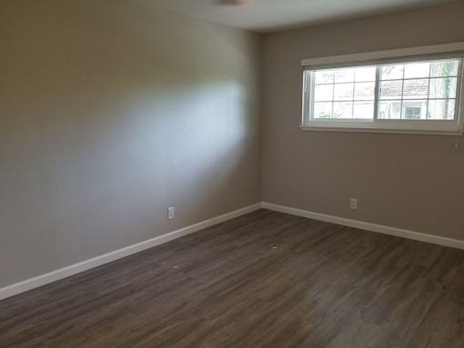 A room with a window and wooden flooring.