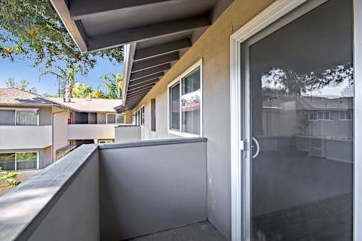 A balcony with a glass door and a grey wall.