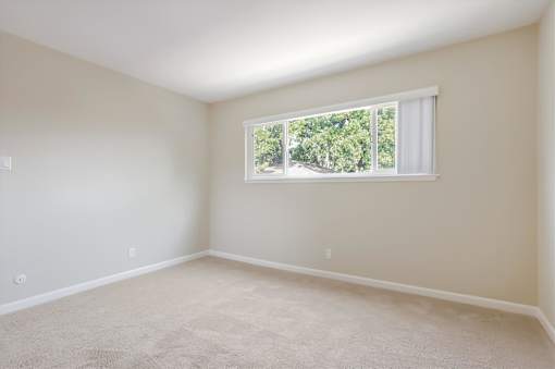 A room with a window and carpeted floor.