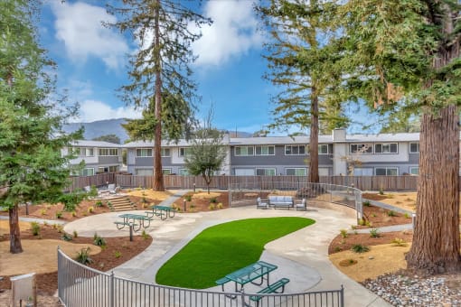 a courtyard with benches and trees in front of an apartment building