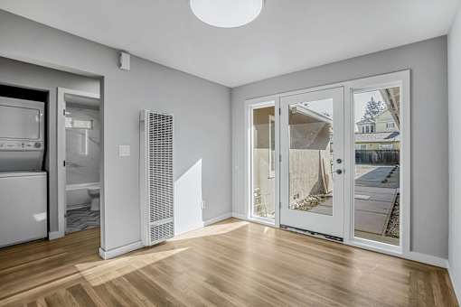 A room with a white wall and a window with a view of a house.