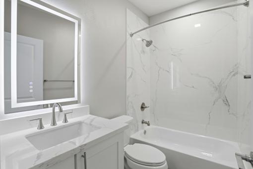 A white bathroom with a marble tub and sink.