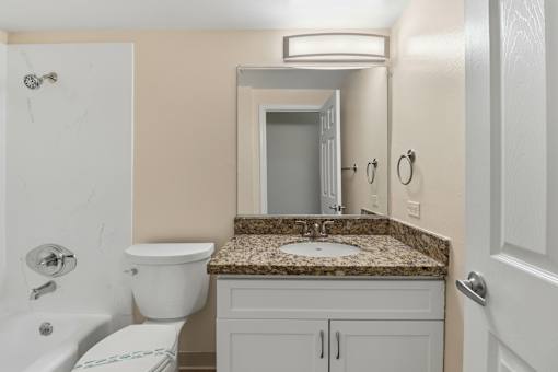 A bathroom with a toilet, sink, and mirror.