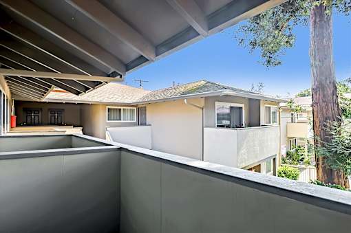 A modern house with a balcony overlooking a tree.