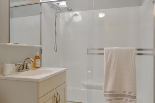 A white towel hangs on a glass shower door.
