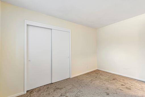 A room with a white door and carpeted floor.