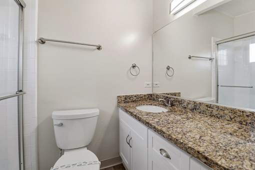 A bathroom with a granite countertop and white fixtures.