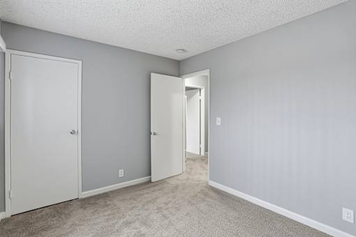 A room with a carpeted floor and two doors.