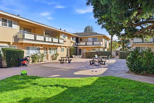 A sunny day at a residential complex with a playground and picnic tables.