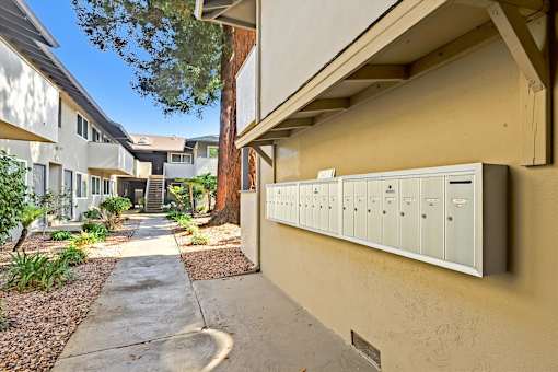 A row of mailboxes on a wall next to a sidewalk.
