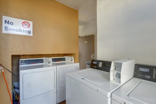 A laundry room with a no smoking sign on the wall.