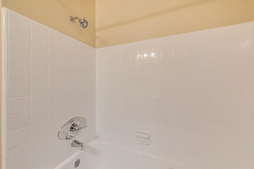 A white bathtub with a shower head and faucet.