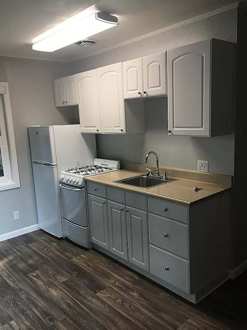 A kitchen with a white refrigerator, a white stove, and white cabinets.